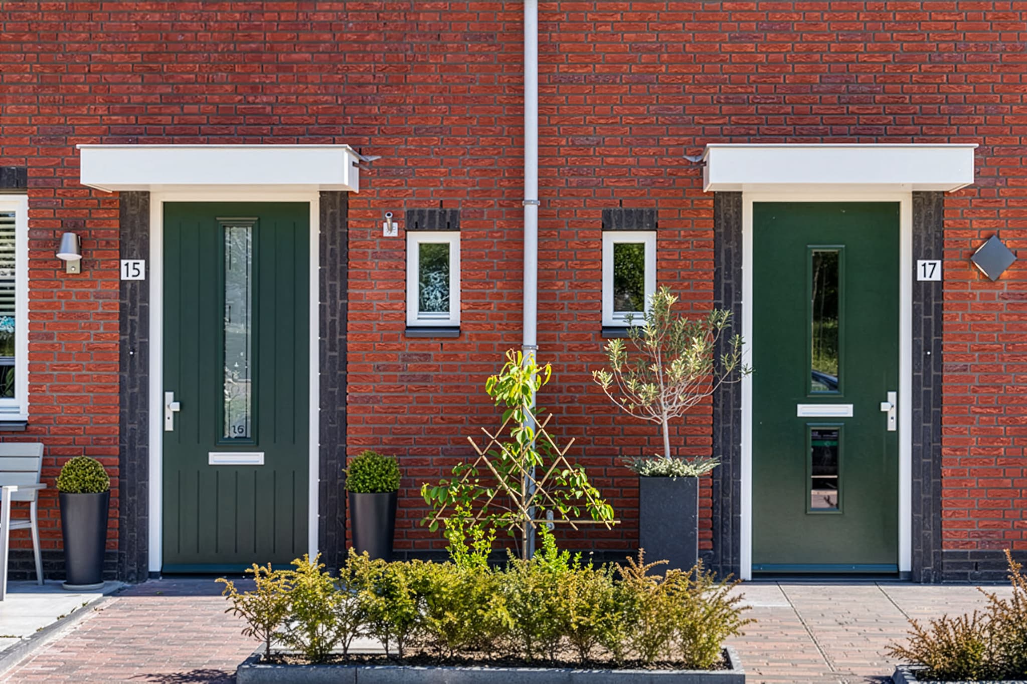Twee donkergroene voordeuren op maat met verticaal glaspaneel in een rode bakstenen gevel